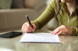 © Antonioguillem - Woman hand signing paper contract on a coffee table