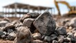 © 69 - Close-up of rough rock stone on construction site ground with blurred heavy machinery and unfinished building structure in background focused on natural texture detail