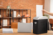 © Pixel-Shot - Female hand destroying paper sheet in shredder on desk in office