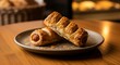 © ALLmost - Two golden-brown sausage rolls, a popular snack, are presented on a rustic plate, showcasing their flaky pastry and savory filling.