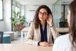 © Asier - Young businesswoman with hand cupped to ear, focused on listening during a business discussion