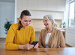 © Lumos sp - Portrait of mother and daughter  having fun, looking at a mobile phone and reading and texting,  sitting and hugging  at home, family life, parenting, love and bonding concepts