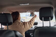 © StokHunt - Woman adjusting her rearview mirror inside a car, ensuring clear visibility for safe and focused driving
