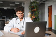 © Serhii - Arab doctor attending online meeting and taking notes on clipboard