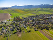 © AmazingAerialAgency - Aerial view of the village with its traditional houses and church tower surrounded by green fields and mountains in Partizanska Lupca, Zilina Region, Slovakia.