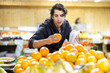 © JackF - Young man buyer choosing fresh oranges in vegetable shop