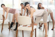 © JackF - Leaning on chair seat with hand foot, girl in tank top and shorts performs lap dance during group workout. Master class on inveiglement men by demonstrating sexy body, pumping skills