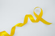 © HAKAROO Project - A long yellow ribbon arranged on a plain white background with copy space. Use for awareness and campaign background designs.