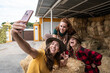 © ADDICTIVE STOCK - Friends taking a smartphone selfie on hay bales at a farm