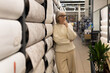 © Ivan Traimak - Mature woman leaning on wallpaper rolls, thoughtfully deciding on home decor