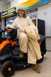 © Ivan Traimak - Senior woman sitting on a new garden tractor, considering purchasing it in a showroom