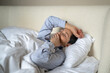 © DimaBerlin - Dreamy senior woman comfortably lying in bed covered in cozy blanket and yawning after waking up in morning, sleepy lazy elderly female awakening at early hours after good night rest and sweet dream.