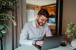 © Dusan - Young man happily working from home using laptop