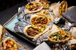 © 9parusnikov - Assorted beef and vegetable wraps wrapped in aluminum foil on a blue platter