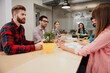 © deagreez - Young creative team in a business meeting around a table in a modern office collaborating on a project