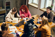© Lustre Art Group  - Young people collaborating around wooden table with laptops and charts. Concept of business planning, creative agency work, student workshop, teamwork, analytics, and office training.