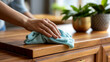 © Kateryna - Macro close up of a single hand using a soft microfiber cloth to wipe dust from a bright softly defocused wooden cabinet surface dust wiping faceless macro gentle wiping