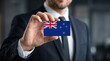 © Monktwins - Businessman holding New Zealand flag card in office, corporate nationality concept.