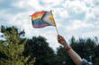 © irissca - Hand holds inclusive pride flag toward sky. LGBTQ Identity, gender expression, authentic self, pride symbol.