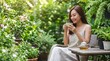 © bayu - Young Asian woman enjoying a peaceful moment with a cup of tea in a beautiful lush green outdoor garden setting on a bright and sunny day.