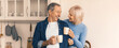 © Prostock-studio - Two people sit close together in a kitchen, smiling at each other while holding coffee cups. The setting has modern features and warm colors. They share a moment of connection in the morning light.