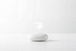 © Taya - Minimalist abstract concept of zero environmental impact with a glowing water drop hovering over a white stone