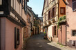 © Oksana - Ribeauville Alsace, France - April 04, 2026 - Calm medieval alleyway bathed in gentle afternoon light with stone walls and timber beams, peaceful old town passage between historic houses
