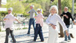 © JackF - Active senior people doing arm swing exercise while practicing healthy lifestyle in open-air