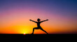 © Valfiyy - Silhouette of a woman practicing yoga warrior pose at sunset with vibrant sky