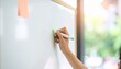 © Anggi - Close-up of a hand writing on a whiteboard with a marker pen, natural light