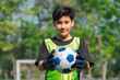 © chokniti - World cup concept with soccer ball or football player, young soccer goalkeeper holding ball, smiling child in sport uniform on outdoor field