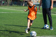 © chokniti - World cup concept with soccer ball or football player, soccer child playing on green field with coach nearby and ball in outdoor sport practice session