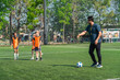 © chokniti - World cup concept with soccer ball or football player, soccer coach training children on field with ball and orange vest, outdoor sport practice for youth players