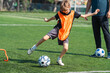 © chokniti - World cup concept with soccer ball or football player, youth soccer practice on outdoor field with child kicking ball and coach nearby