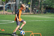 © chokniti - World cup concept with soccer ball or football player, young boy practicing soccer on green field with hurdle drills and ball