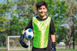 © chokniti - World cup concept with soccer ball or football player, youth soccer player standing on field with ball and goal, smiling in sunny outdoor training