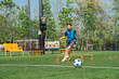 © chokniti - World cup concept with soccer ball or football player, youth soccer player practices hurdle drill on outdoor field in sunny park