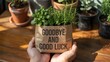 © Fatimazahra7788356 - Person holding small potted plant with cosmetic and good luck message indoors