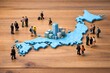 © Jumpei - 日本地図のジオラマの上でビジネスマンや観光客が交流する日本の社会と経済のイメージ