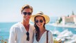 © Farah - Happy young couple wearing fashionable sunglasses and straw hat posing for a bright summer photograph near the blue mediterranean sea