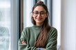 © Khawla - A close up head shot portrait of a preppy, young, beautiful, confident and attractive Indian Asian woman in a green sweater and spectacles in a classroom or office. She is smiling happily
