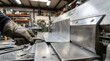 © Mahmuda - industrial sheet metal bending process | worker in protective leather gloves using press brake | precision metal fabrication in workshop | hand pressing steel plate into shape