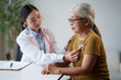 © Tj - Asian doctor examining an elderly female patient with a stethoscope during a detailed medical checkup, providing attentive healthcare and support in a clinic