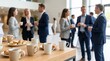 © Olga Ко - Coffee break at a networking business event. Close-up of coffee cups and pastries on a catering table with a blurred background of corporate professionals networking in a modern office lobby