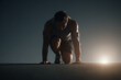 © Fox - Athletic man in sportswear prepares to sprint at dawn, crouched in a starting position on an outdoor track. Focused runner readies himself for an intense early morning workout session