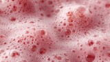 Close-up of pink foam with bubbles. The texture is smooth and creamy, resembling a frothy beverage or dessert topping.