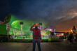 © Julian - Woman watching carnival ride at sunset with motion blur lights