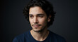 © sulam - Pensive Young Man with Dark Curly Hair Against a Dark Background