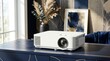 © Megin Design - 高級感のある室内に置かれた白いプロジェクター。青と金のインテリアとホームシアター機器。現代的なプレゼンテーションと映像技術
