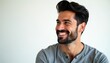 © Viktor - Man smiles broadly showing teeth, looking to side. He has dark hair and beard, wearing grey casual shirt against white background. His expression is happy and confident.